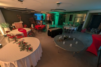 Salle moderne avec tables hautes blanches, éclairage coloré et murs vitrés, prête pour un événement.