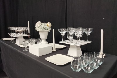 Salle moderne avec tables hautes blanches, éclairage coloré et murs vitrés, prête pour un événement.