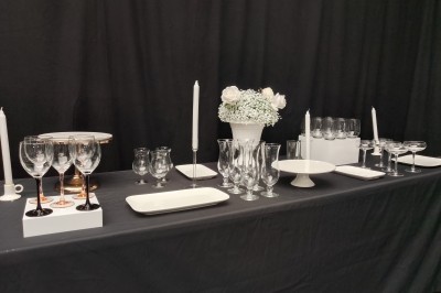 Salle moderne avec tables hautes blanches, éclairage coloré et murs vitrés, prête pour un événement.