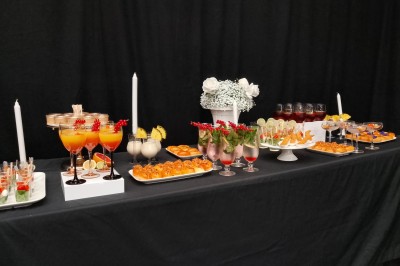 Salle moderne avec tables hautes blanches, éclairage coloré et murs vitrés, prête pour un événement.