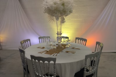 Salle moderne avec tables hautes blanches, éclairage coloré et murs vitrés, prête pour un événement.