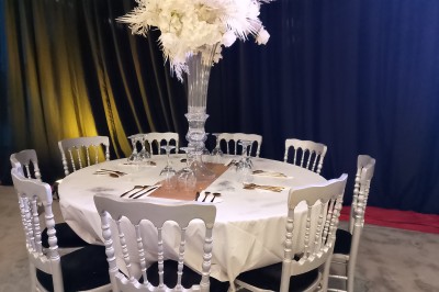 Salle moderne avec tables hautes blanches, éclairage coloré et murs vitrés, prête pour un événement.