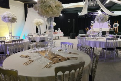 Salle moderne avec tables hautes blanches, éclairage coloré et murs vitrés, prête pour un événement.