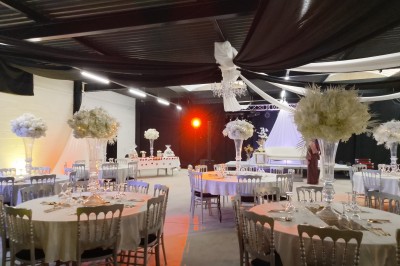 Salle moderne avec tables hautes blanches, éclairage coloré et murs vitrés, prête pour un événement.