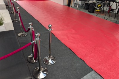 Salle moderne avec tables hautes blanches, éclairage coloré et murs vitrés, prête pour un événement.