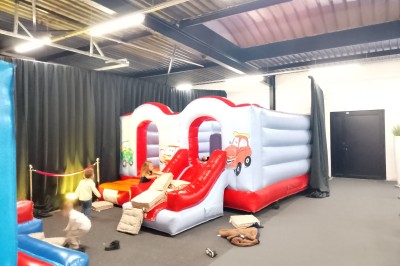 Un Père Noël décoratif près d'un sapin orné de boules argentées et de guirlandes rouges, dans un décor festif.