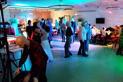 Un Père Noël décoratif près d'un sapin orné de boules argentées et de guirlandes rouges, dans un décor festif.