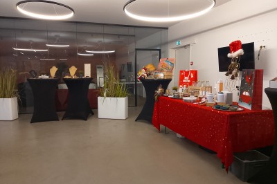 Un Père Noël décoratif près d'un sapin orné de boules argentées et de guirlandes rouges, dans un décor festif.