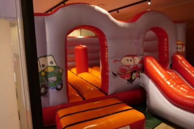 Un Père Noël décoratif près d'un sapin orné de boules argentées et de guirlandes rouges, dans un décor festif.