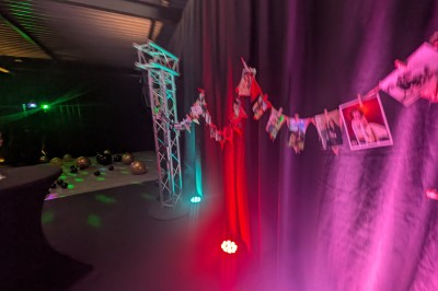 Un Père Noël décoratif près d'un sapin orné de boules argentées et de guirlandes rouges, dans un décor festif.