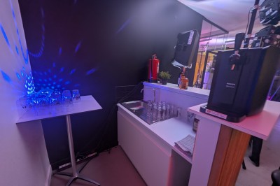 Un Père Noël décoratif près d'un sapin orné de boules argentées et de guirlandes rouges, dans un décor festif.