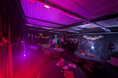 Un Père Noël décoratif près d'un sapin orné de boules argentées et de guirlandes rouges, dans un décor festif.