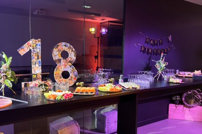 Un Père Noël décoratif près d'un sapin orné de boules argentées et de guirlandes rouges, dans un décor festif.