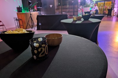 Un Père Noël décoratif près d'un sapin orné de boules argentées et de guirlandes rouges, dans un décor festif.