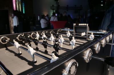Un grand groupe de jeunes assis dehors sur un sol en béton, près de bâtiments sous un ciel nuageux.