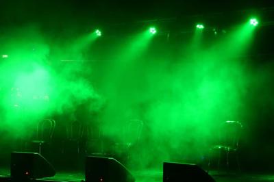 Un grand groupe de jeunes assis dehors sur un sol en béton, près de bâtiments sous un ciel nuageux.