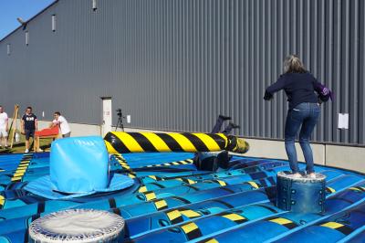 Un grand groupe de jeunes assis dehors sur un sol en béton, près de bâtiments sous un ciel nuageux.