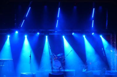 Un grand groupe de jeunes assis dehors sur un sol en béton, près de bâtiments sous un ciel nuageux.