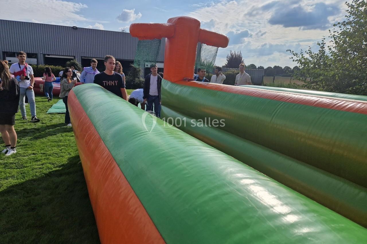 Structure gonflable colorée utilisée lors d'un événement en plein air, entourée de participants.