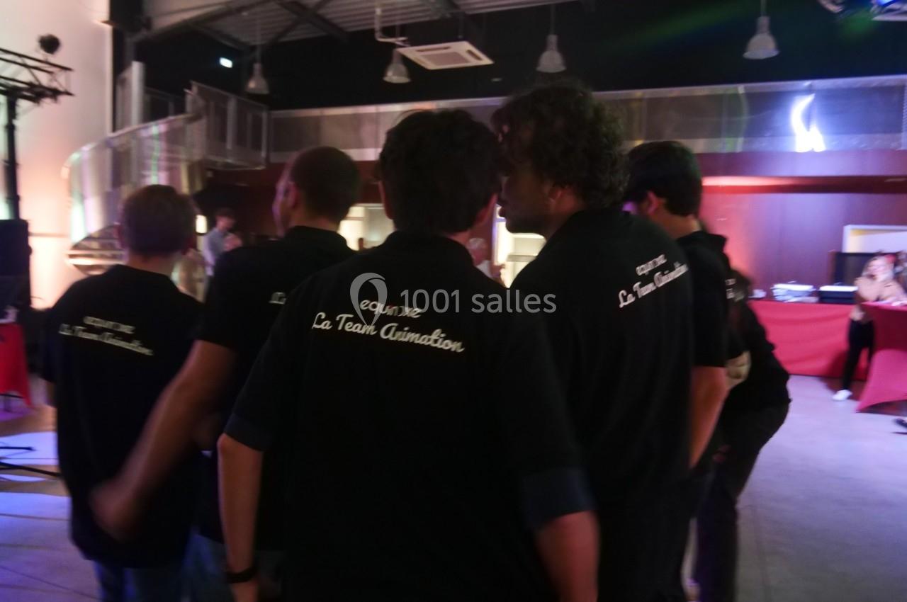 Un groupe de personnes portant des polos noirs avec l'inscription ’La Team Animation’ dans un espace intérieur éclairé.