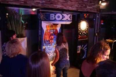 Un grand groupe de jeunes assis dehors sur un sol en béton, près de bâtiments sous un ciel nuageux.