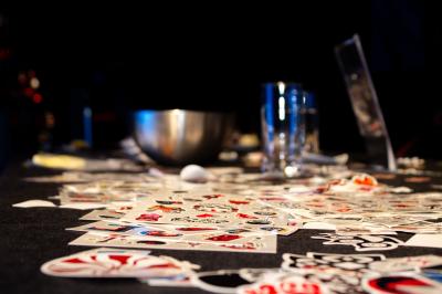 Un grand groupe de jeunes assis dehors sur un sol en béton, près de bâtiments sous un ciel nuageux.
