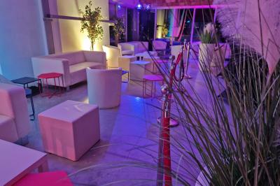 Un grand groupe de jeunes assis dehors sur un sol en béton, près de bâtiments sous un ciel nuageux.