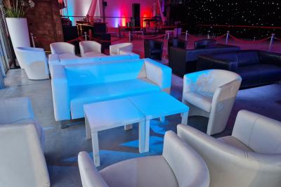 Un grand groupe de jeunes assis dehors sur un sol en béton, près de bâtiments sous un ciel nuageux.