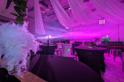 Un grand groupe de jeunes assis dehors sur un sol en béton, près de bâtiments sous un ciel nuageux.