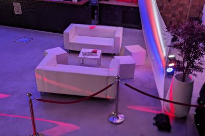 Un grand groupe de jeunes assis dehors sur un sol en béton, près de bâtiments sous un ciel nuageux.