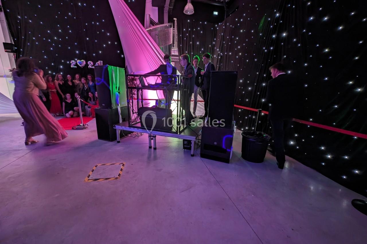 Un DJ anime une soirée dans une salle décorée de lumières étoilées, avec des invités en tenue de soirée.