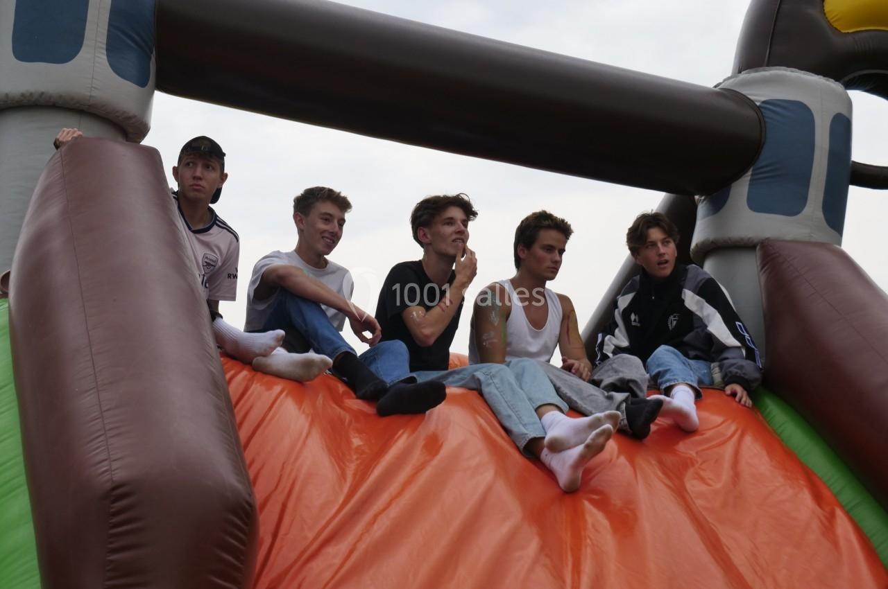 Six jeunes assis en haut d'une structure gonflable colorée, regardant dans différentes directions.