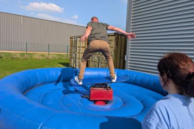 Un grand groupe de jeunes assis dehors sur un sol en béton, près de bâtiments sous un ciel nuageux.