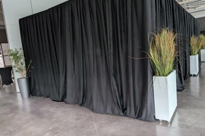 Un grand groupe de jeunes assis dehors sur un sol en béton, près de bâtiments sous un ciel nuageux.