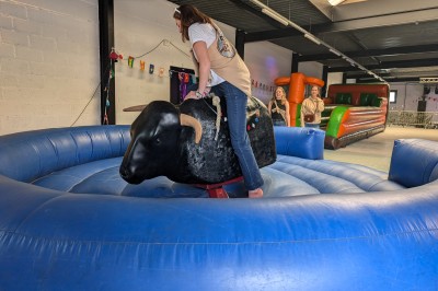 Un grand groupe de jeunes assis dehors sur un sol en béton, près de bâtiments sous un ciel nuageux.