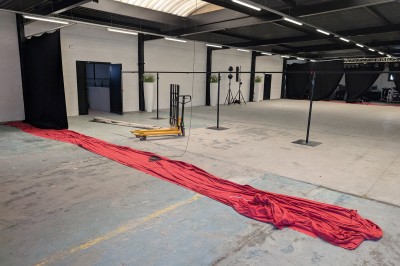 Un grand groupe de jeunes assis dehors sur un sol en béton, près de bâtiments sous un ciel nuageux.