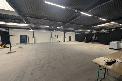 Un grand groupe de jeunes assis dehors sur un sol en béton, près de bâtiments sous un ciel nuageux.