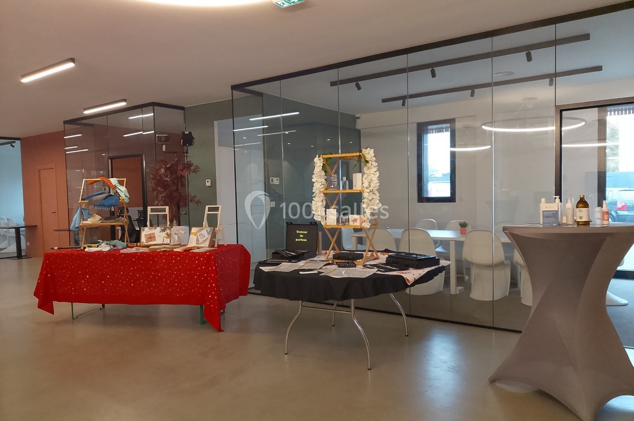 Tables décorées avec des objets artisanaux et des produits exposés dans une salle moderne avec des cloisons vitrées.