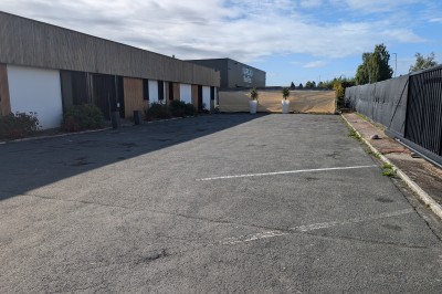 Un grand groupe de jeunes assis dehors sur un sol en béton, près de bâtiments sous un ciel nuageux.