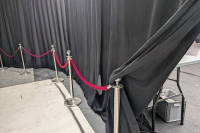 Un grand groupe de jeunes assis dehors sur un sol en béton, près de bâtiments sous un ciel nuageux.