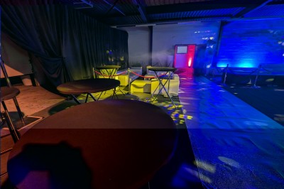 Un grand groupe de jeunes assis dehors sur un sol en béton, près de bâtiments sous un ciel nuageux.