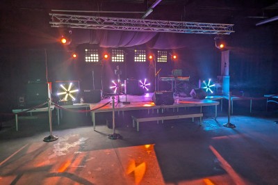 Un grand groupe de jeunes assis dehors sur un sol en béton, près de bâtiments sous un ciel nuageux.