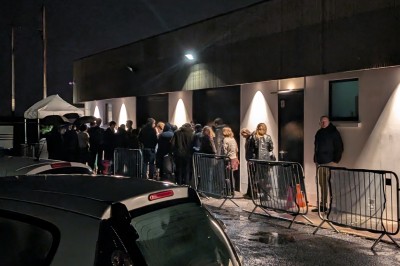 Des enfants colorient des dessins autour d'une table ronde, entourés d'adultes dans un espace intérieur animé.