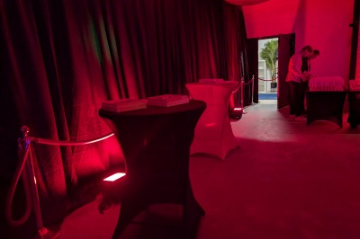 Des enfants colorient des dessins autour d'une table ronde, entourés d'adultes dans un espace intérieur animé.