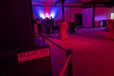 Des enfants colorient des dessins autour d'une table ronde, entourés d'adultes dans un espace intérieur animé.