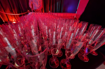 Des enfants colorient des dessins autour d'une table ronde, entourés d'adultes dans un espace intérieur animé.