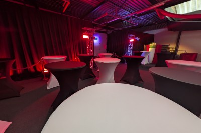 Des enfants colorient des dessins autour d'une table ronde, entourés d'adultes dans un espace intérieur animé.