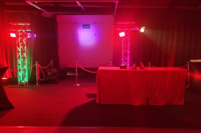 Des enfants colorient des dessins autour d'une table ronde, entourés d'adultes dans un espace intérieur animé.