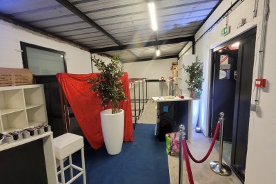 Des enfants colorient des dessins autour d'une table ronde, entourés d'adultes dans un espace intérieur animé.