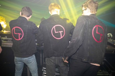 Des enfants colorient des dessins autour d'une table ronde, entourés d'adultes dans un espace intérieur animé.